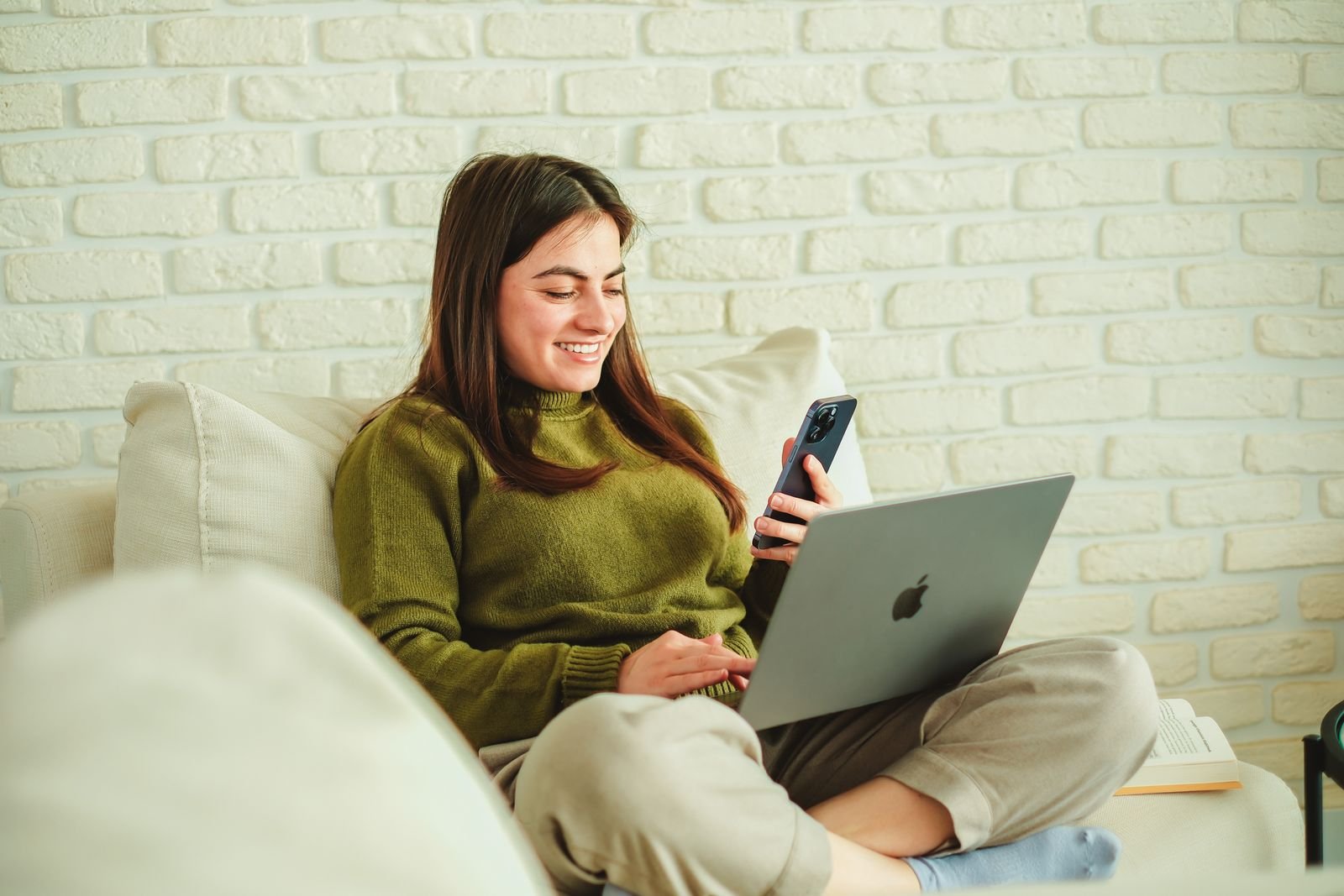 Woman using a laptop and smartphone side by side at home