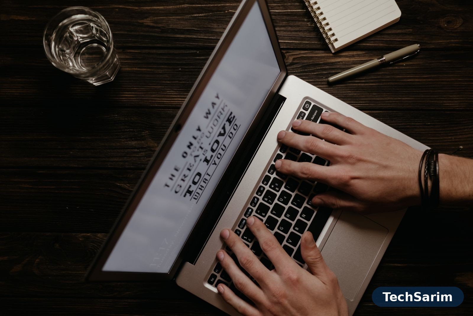 Hands on a laptop keyboard with an inspirational quote on the screen, seen from above