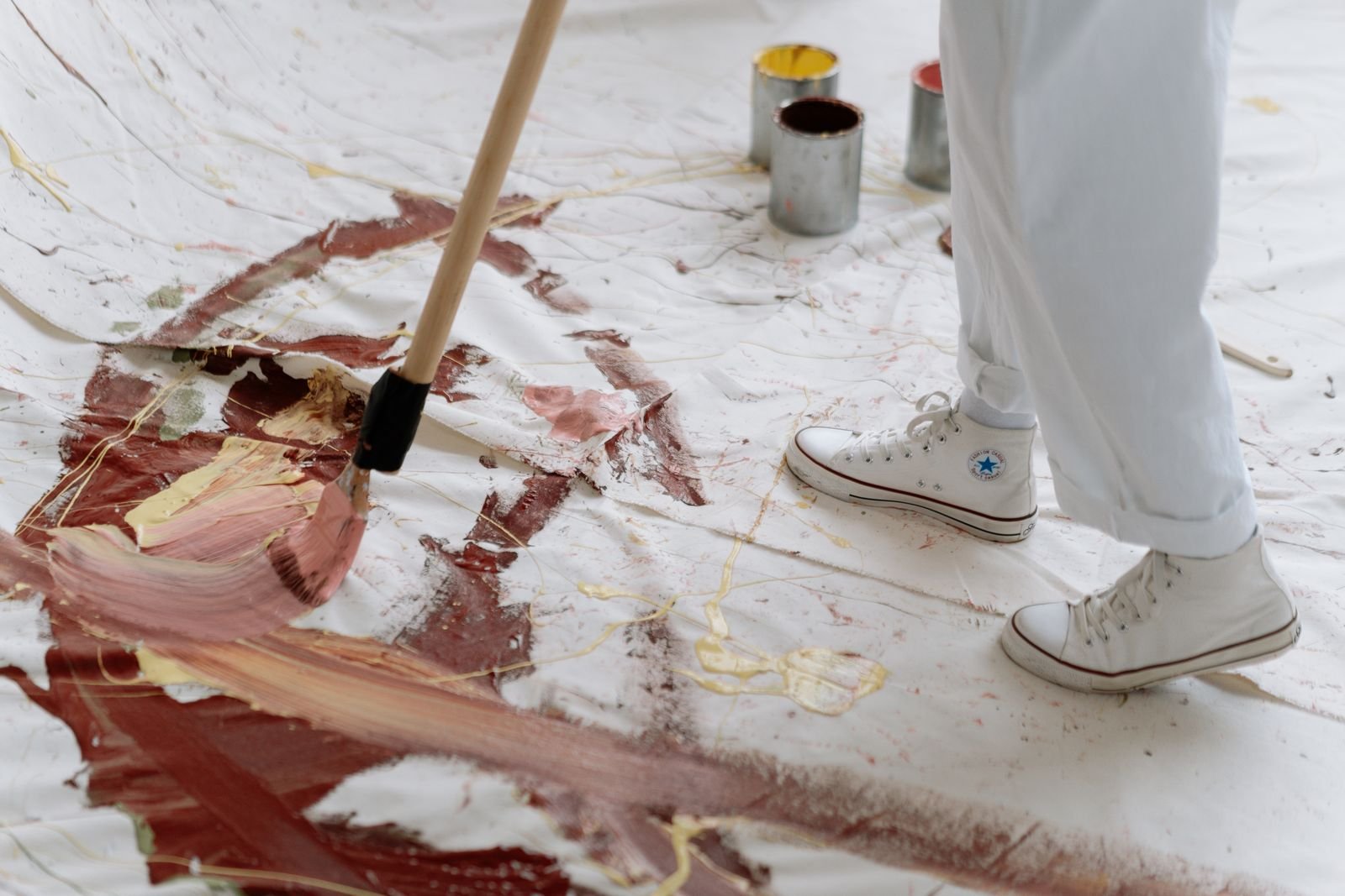 Artist painting abstract patterns on a large canvas on the studio floor