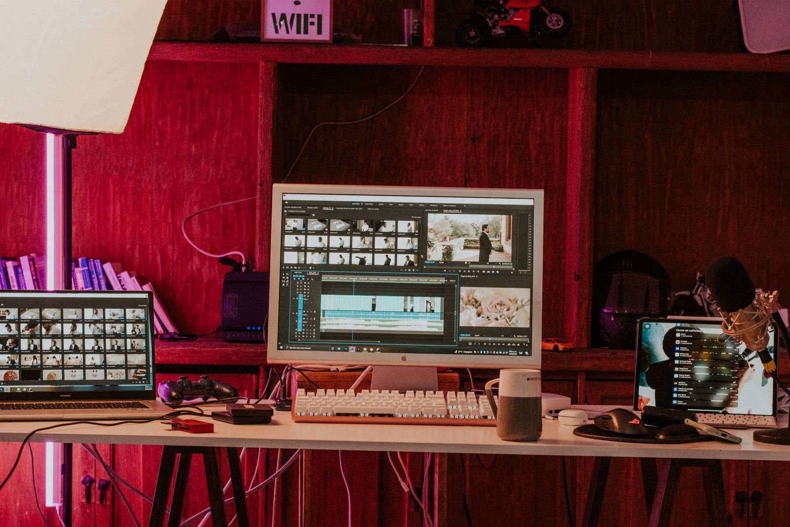A professional video editing workspace with monitors, a keyboard and studio microphones