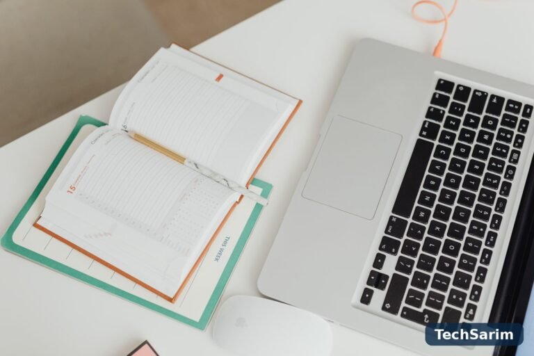Top view of a clean, organised desk with a laptop, notebook and mouse