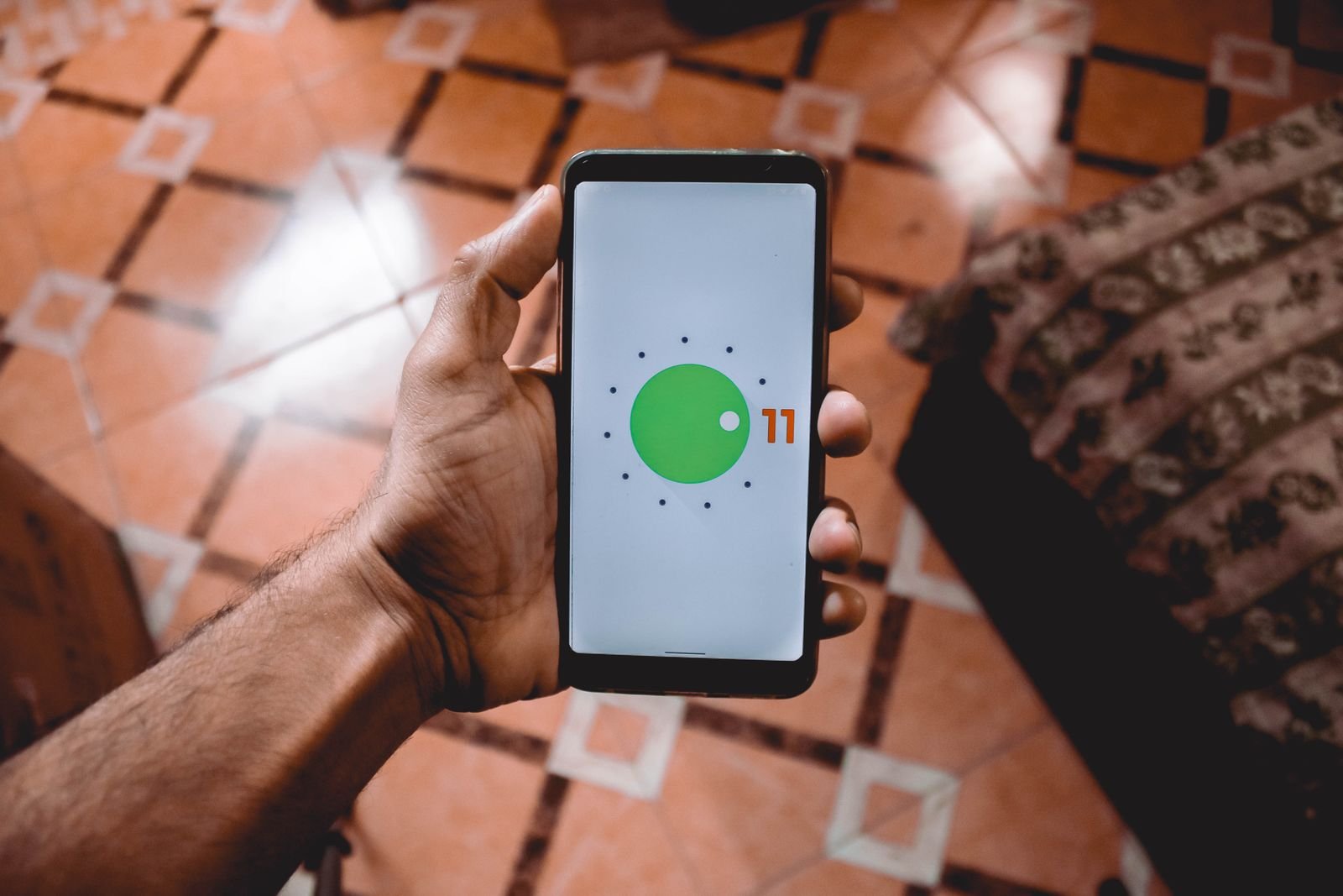 A hand holding an Android phone showing the Android logo on its screen