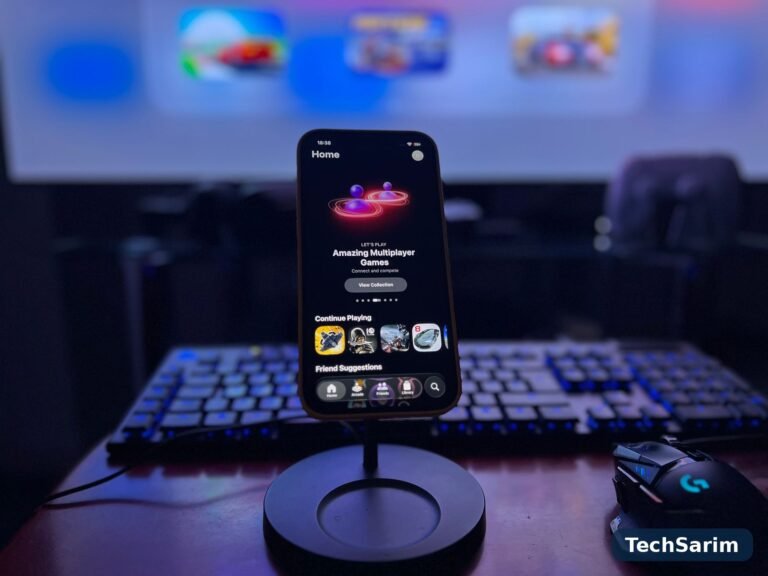 A smartphone on a stand showing a games library, in front of a gaming keyboard and mouse