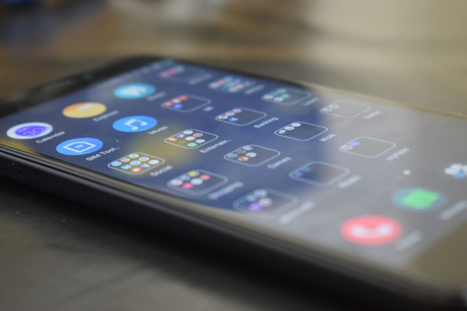 An Android phone lying on a table showing app folders for social, banking, work and games