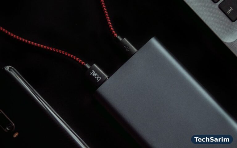 A smartphone connected by a red braided USB cable next to a laptop