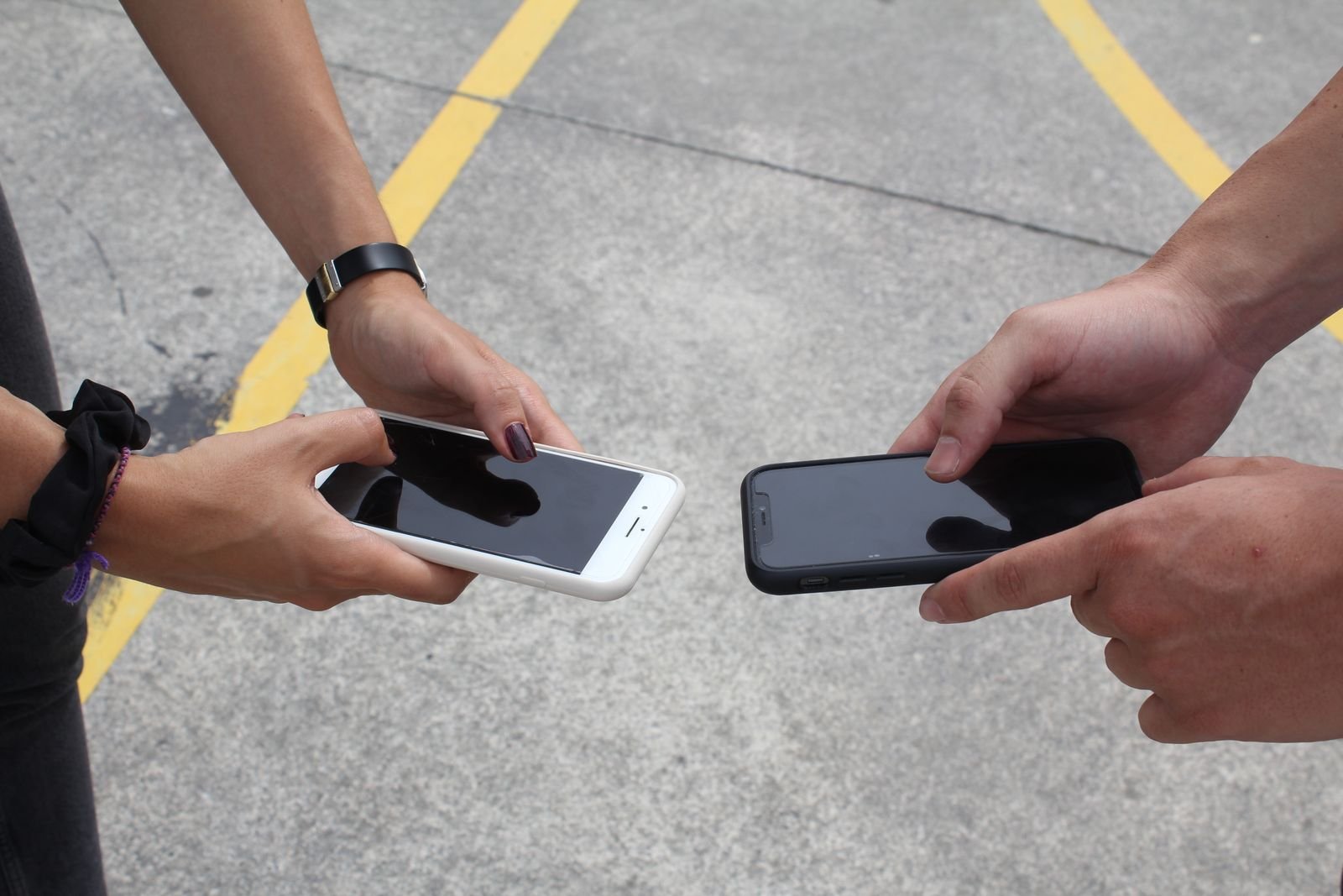 Two people comparing smartphones held face to face outdoors