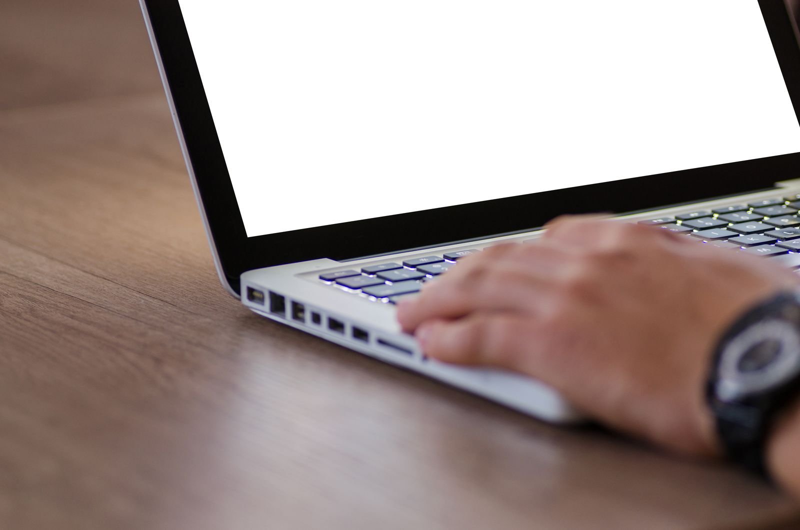 Close-up of a hand on a laptop keyboard with a bright blank screen