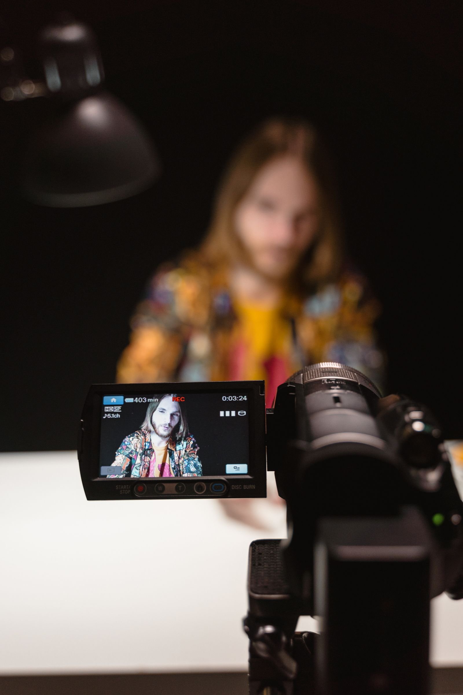 A vlogger recording a video indoors with a camera on a tripod
