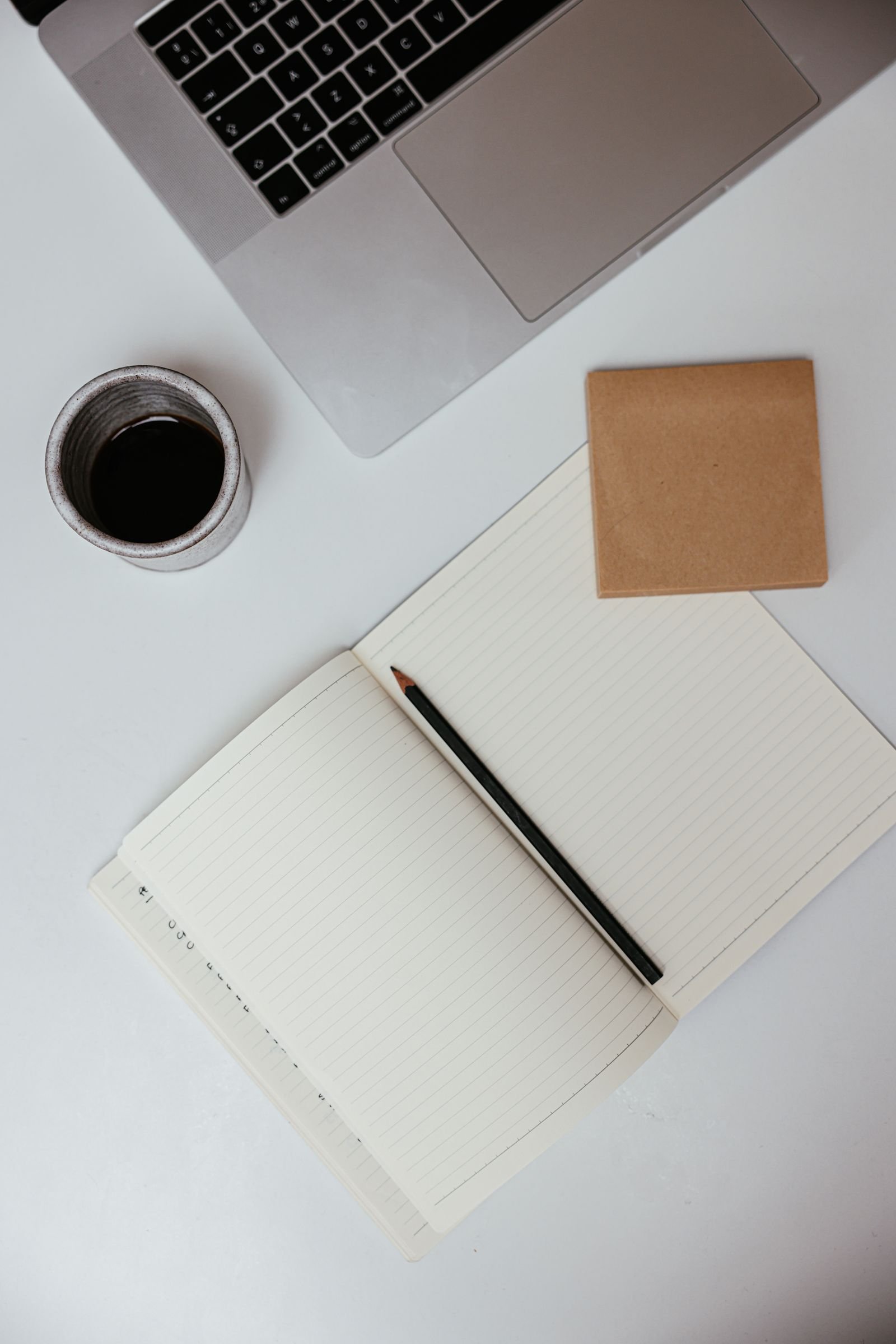 Flat lay of a workspace with a laptop, notebook and coffee — the everyday tools behind a simple productivity setup