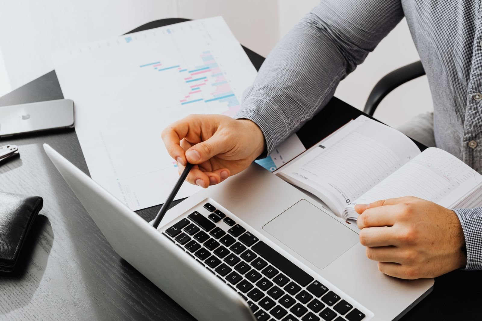 A professional reviewing documents beside a laptop at an office desk, working through the day's tasks