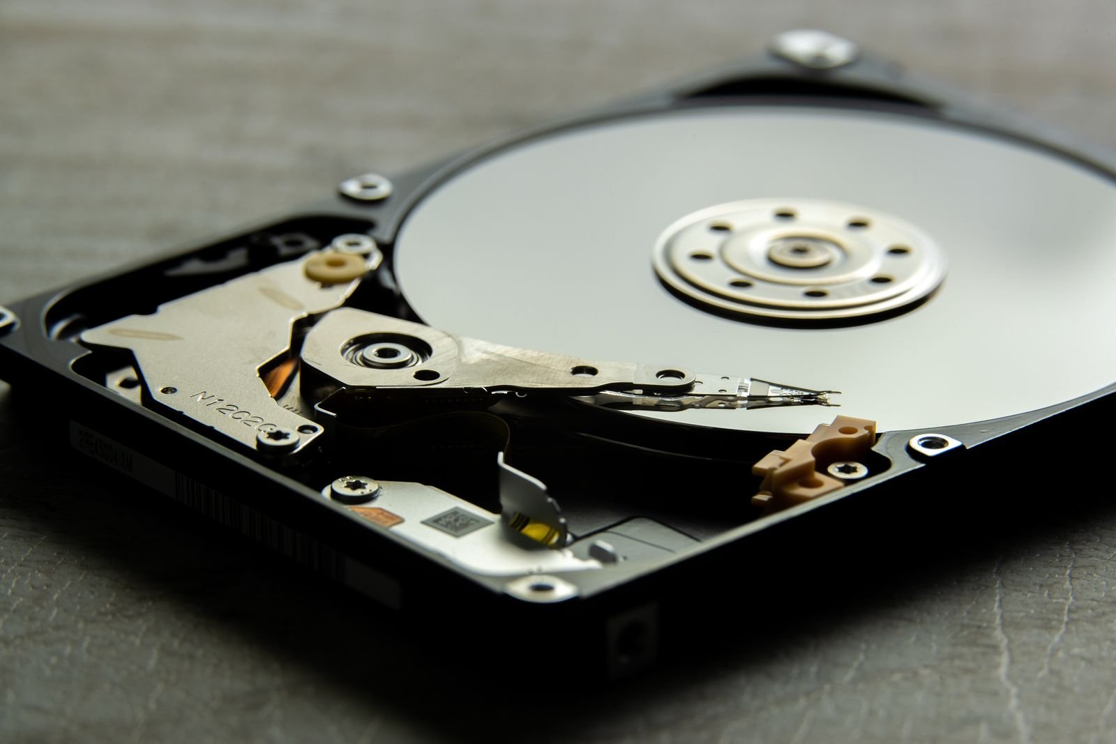 Close-up of an open hard disk drive showing its mirror-like platter and the actuator arm with the read/write head