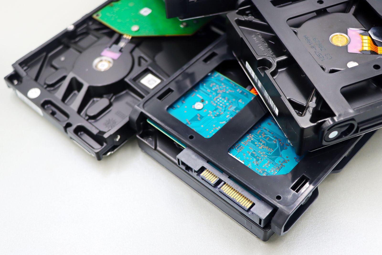 A stack of 3.5-inch internal hard disk drives with exposed circuit boards on a white surface
