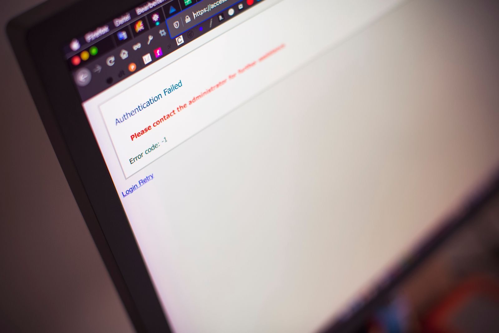 A laptop screen showing an Authentication Failed error message with a login retry link, photographed at an angle