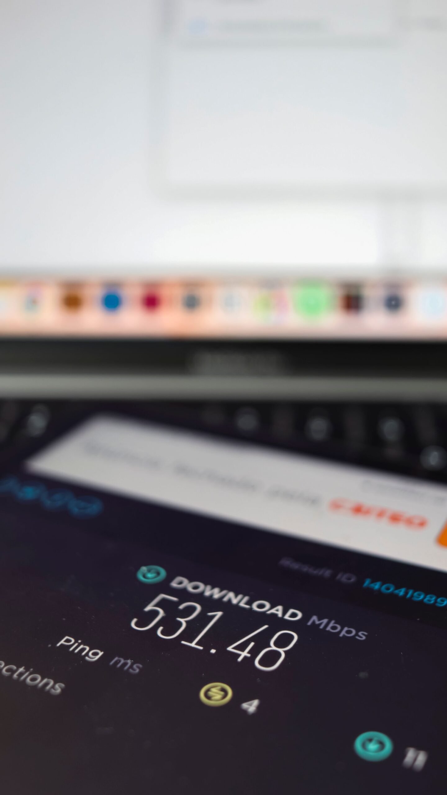 Close-up of a laptop screen showing an internet speed test result of about 530 Mbps download with a 4 ms ping