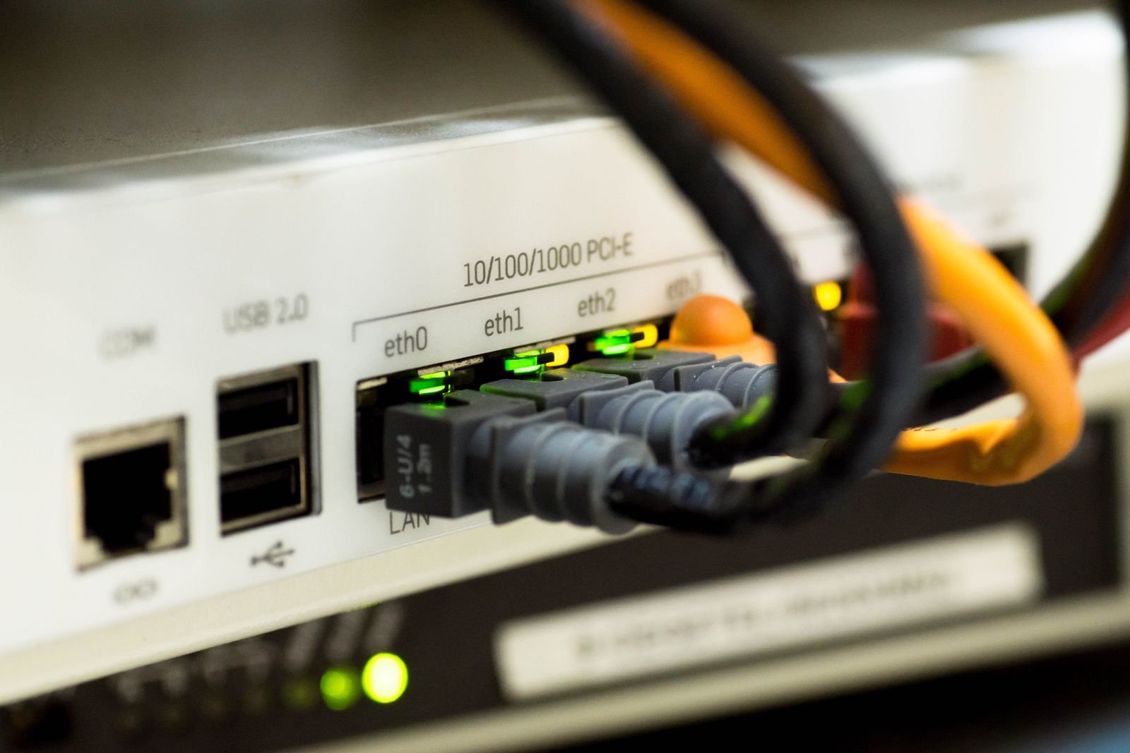 Close-up of Ethernet cables plugged into the labelled LAN ports on the back of a router, with green activity lights glowing