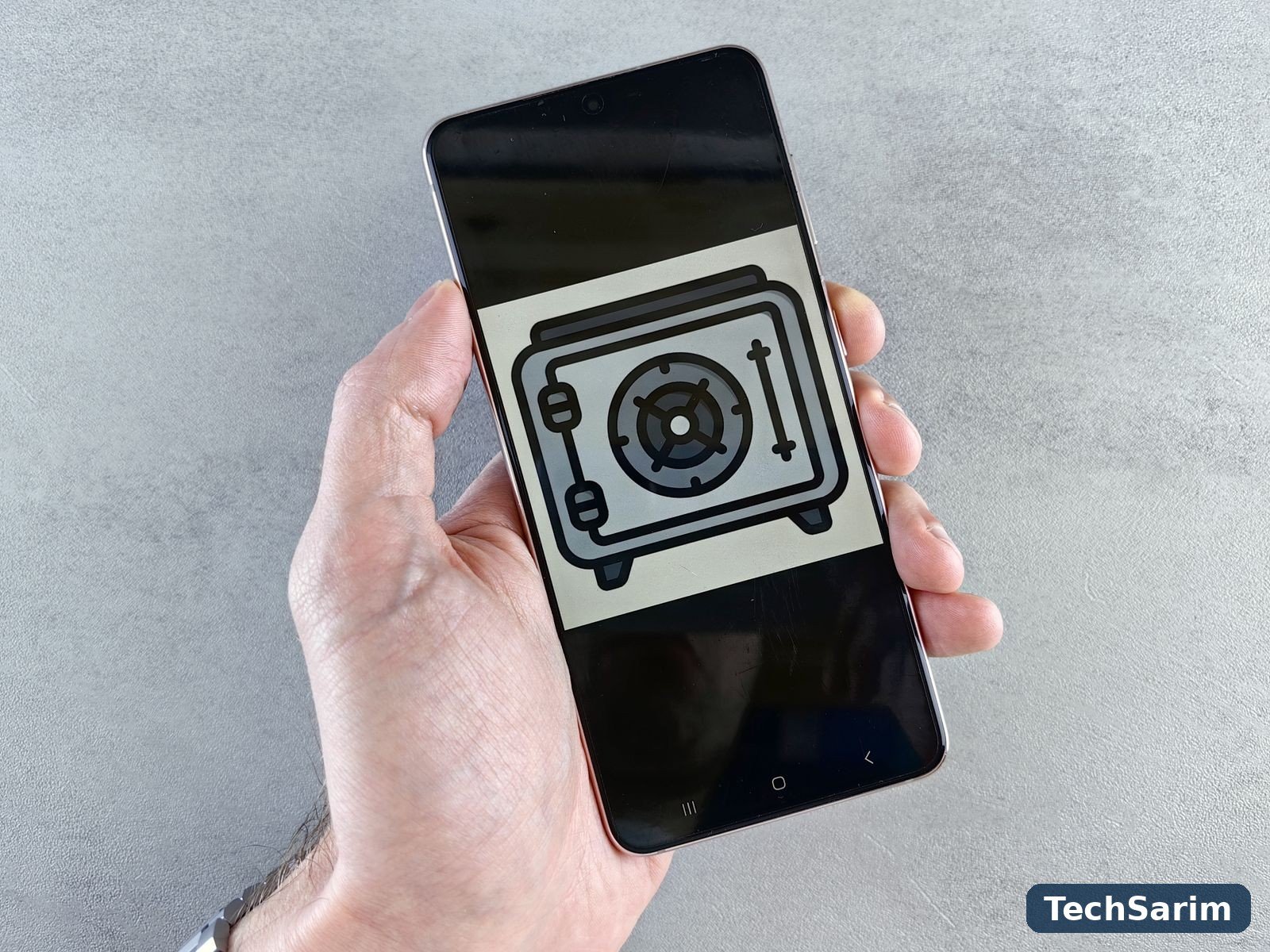 A hand holding an Android smartphone displaying a large safe icon, symbolising the phone as a locked vault