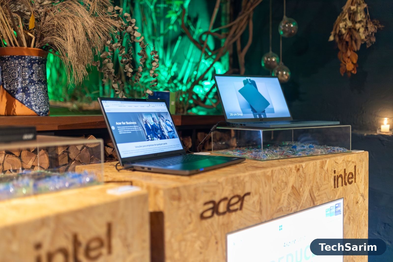 Two laptops on raised display stands at a tech showroom, with Acer and Intel branding on the wooden display counters
